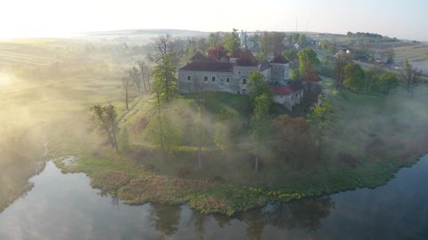 Aerial view of Svirzh castle near Lviv, Ukraine at dawn. Lake, morning fog and surrounding landscape at sunrise.
