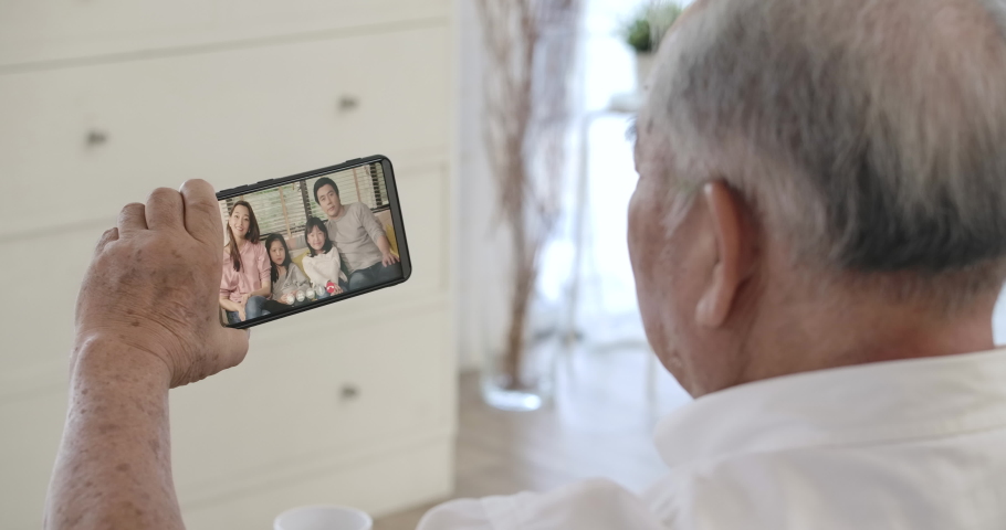 Over shoulder closeup view of asian senior elderly 70s man user holding smart phone watching mobile video calling family in virtual app, older grandparent learn using modern technology gadget concept. | Shutterstock HD Video #1053894389