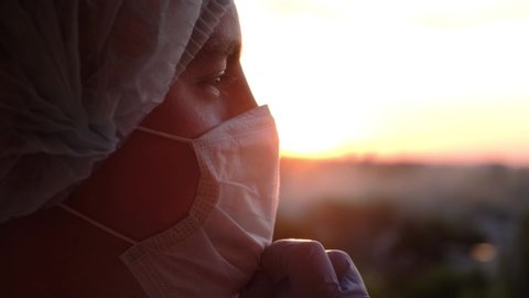 Doctor taking off protective mask at sunset and smiling, close-up