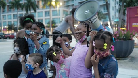 Miami Downtown, FL, USA - JUNE 7, 2020: Black family with children during a demonstration against racism. School girl speaks to the speaker at the protest.
