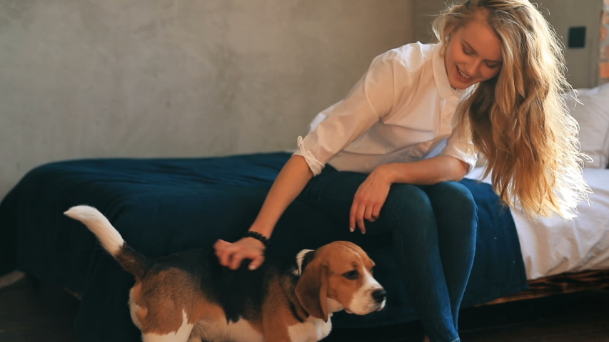 Portrait of beautiful young woman with dog playing at home.