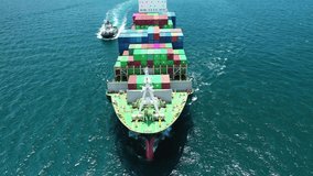 Aerial drone video of huge Container cargo Ship carrying load in truck-size colourful containers cruising deep blue sea near port of Piraeus, Attica. Greece