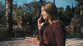 Tracking around shot of casual girl emotionally talking with boyfriend on phone outdoor
