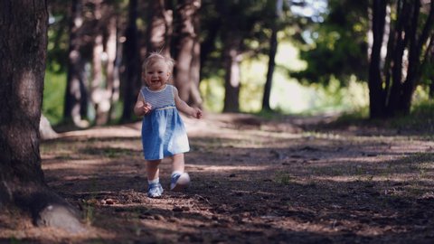 first steps of a one-year-old child in a forest or park