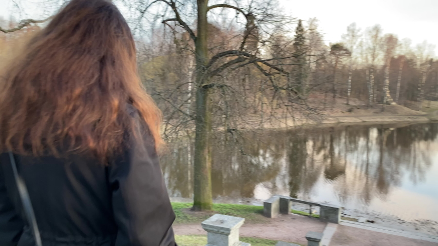 Rear view of woman walking down stone steps to Marienthal pond in Pavlovsk park, Saint Petersburg, Russia