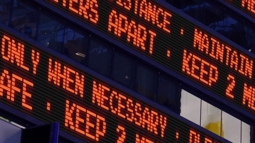 Closeup view of a news ticker reminding pedestrians to keep 2 meters apart from each other. Social distancing was a common practice to slow the spread of COVID-19 during the pandemic of 2020.  	 Royalty-Free Stock Footage #1053913475