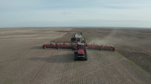 A Seeder Tractor Seeding At The Farmland In Swift Current, Saskatchewan, Canada - ascending drone shot