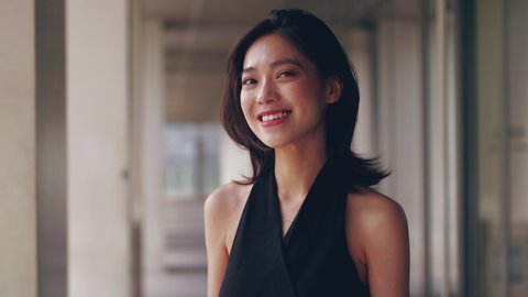 Close up side view of one young beautiful Chinese woman looking at camera smile attractive elegant Asian lady in black dress portrait 4k slow motion