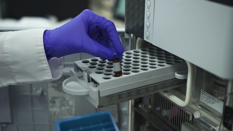 Modern biochemical analyzer filled with test tubes. spbd Genetics worker putting inserting test tubes bottles with dna into the pcr thermal cycler or amplifier for diagnostics. concept pharmaceutical