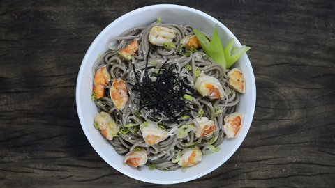 Soba Noodles with Shrimps and shoyu soy sauce Japanese Food Fusion Style sprinkle white sesame and seaweed decorate leek top view