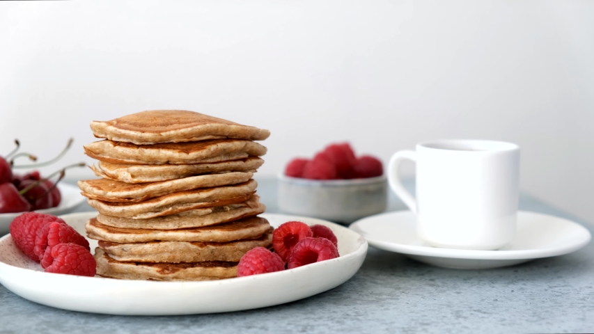 Syrup pouring on pancakes. Stack of american pancakes served with raspberry, cherry and maple syrup. Tasty sweet breakfast food Royalty-Free Stock Footage #1053928592