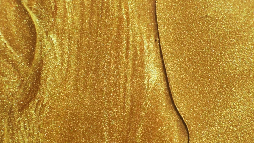 Glitter fluid motion. Molten gold. Sparkling yellow liquid paint flow overlay.