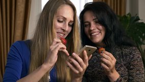 Two Female Friends Eat Strawberries while Chatting Sharing and Watching Social Media on Smartphone at Home. 2x Slow motion - 0.5 speed 60 FPS