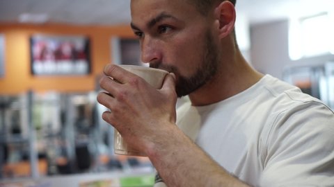 An athlete drinks a mixture of protein after a workout in the gym