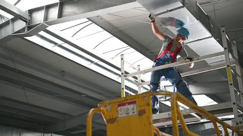 Caucasian Male Worker Inspecting Hvac Air Duct System Installed On Ceiling Inside Of New Construction Site.