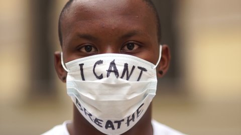 Outdoor portrait of a African American in a medical mask with the inscription I cant breathe. Black lives matter, mass protests against racism in the USA and Europe