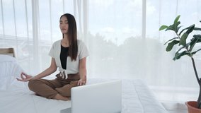 Asian teenage girl in casual wear are meditating sitting with Computer laptop on bed. young woman doing yoga exercise at home for stress relief relaxing from work. Slow motion Dolly slider shot - Powered by Shutterstock - Get 15% off with code: PIKWIZARD15