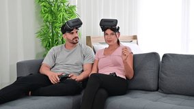 4K Young happy couple playing video games wearing virtual reality glasses