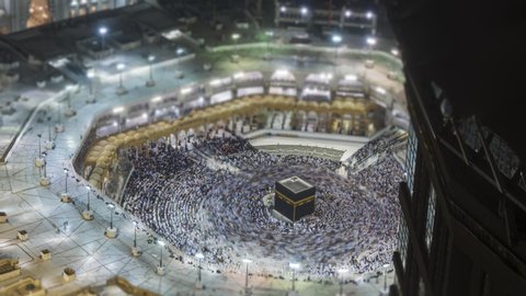 Tilt shift Time lapse sunrise of Muslim pilgrims circling around the holy Kaaba at dawn and praying inside al Masjid al Haram in Mecca, Saudi Arabia. Zoom out motion timelapse. Prores UHD