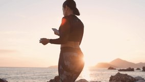 sporty woman using phone on beach. Fitness model with smartphone on beach at sunset time