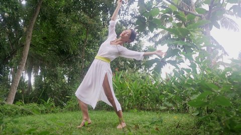 mind and body connection - beautiful and happy healer Asian woman holding star symbol doing ritual traditional healing dance at green tropical forest in wellness and healthy lifestyle 