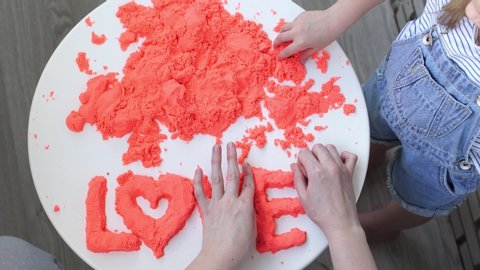 hand molded of red kinetic sand the word love and spread. the development of fine motor skills. educational games