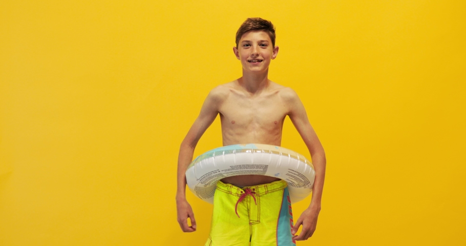 Happy teen guy, standing with an inflatable sea circle and celebrating victory, isolated on a yellow background Royalty-Free Stock Footage #1053953519