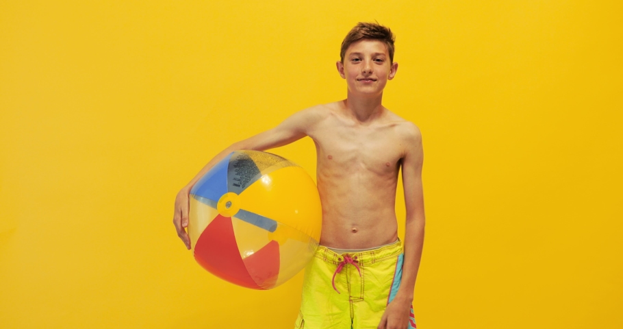 excited teen guy having fun and dancing with an inflatable sea ball, on a yellow background Royalty-Free Stock Footage #1053953543