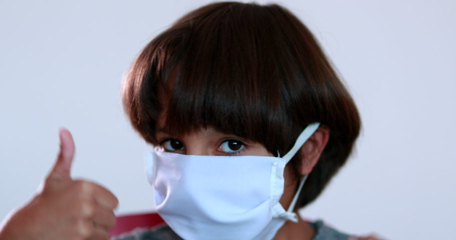 Child wearing surgical mask giving thumbs up, kid portrait wearing pandemic mask Royalty-Free Stock Footage #1053954260