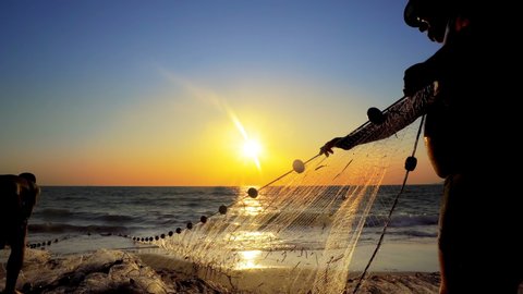 Fishermen fishing in the early morning golden light manual hand pulling the net