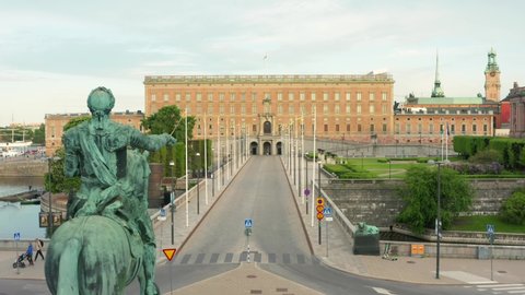 Stockholm palace and statue drone view sunny summer day. Sweden flags in background national day celebration. Aerial shot of royal castle building in Swedish capital city. Gustav Adolfs public square