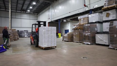 CIRCA 2020 - Rhode Island National Guard and FEMA workers track Covid-19 coronavirus equipment inventory and ship supplies in warehouse with forklift.