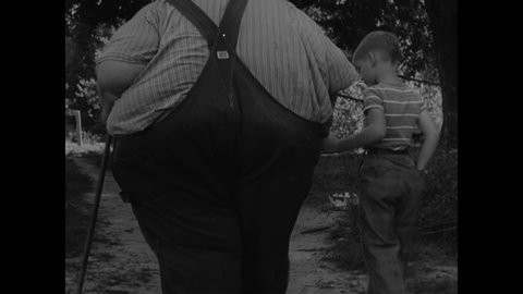 CIRCA 1946 - Robert Earl Hughes, the world's heaviest man, is seen feeding chickens at his family's farm in rural Illinois.