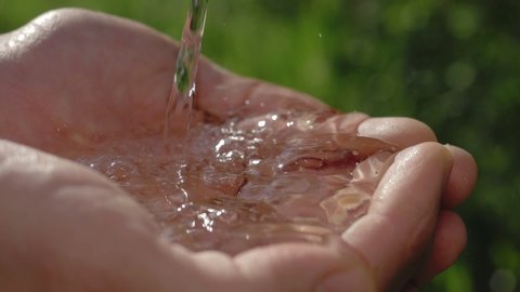 clean water in human hands. stream of pure water pouring into male hands. water drops, water resources, earth, environment. conservation of natural resources.