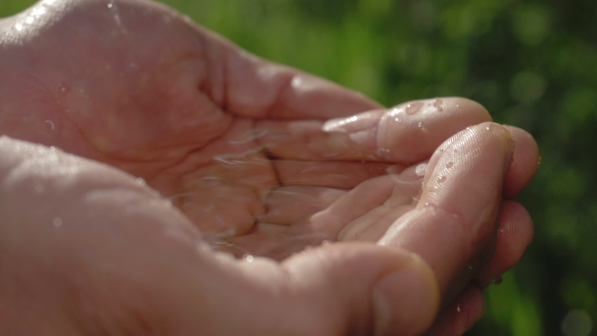 Clean water in human hands. stream of pure water pouring into male hands. water drops, water resources, earth, environment. conservation of natural resources. | Shutterstock HD Video #1053960956