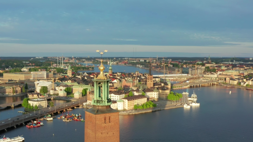 Stockholm City Hall drone shot on beautiful summer evening. Golden crowns close up and rooftop. Old town palace and city center in background. Sunset light over Stadshuset in Sweden capital Royalty-Free Stock Footage #1053961079