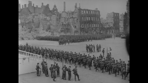 CIRCA 1945 - Victorious American soldiers pass for review in the ruins of a war-torn German city.