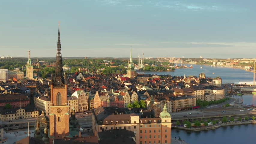 Stockholm old town drone shot on summer evening at sunset. Rooftops and old buildings from above. Riddarholm German church and ocean overview video. gamla stan city center in Sweden capital city Royalty-Free Stock Footage #1053961952