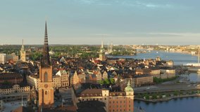 Stockholm old town drone shot on summer evening at sunset. Rooftops and old buildings from above. Riddarholm German church and ocean overview video. gamla stan city center in Sweden capital city