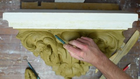 Sculptor create clay model of a Corinthian capitel with scrolls and unfurled acanthus leaves in restoration workshop