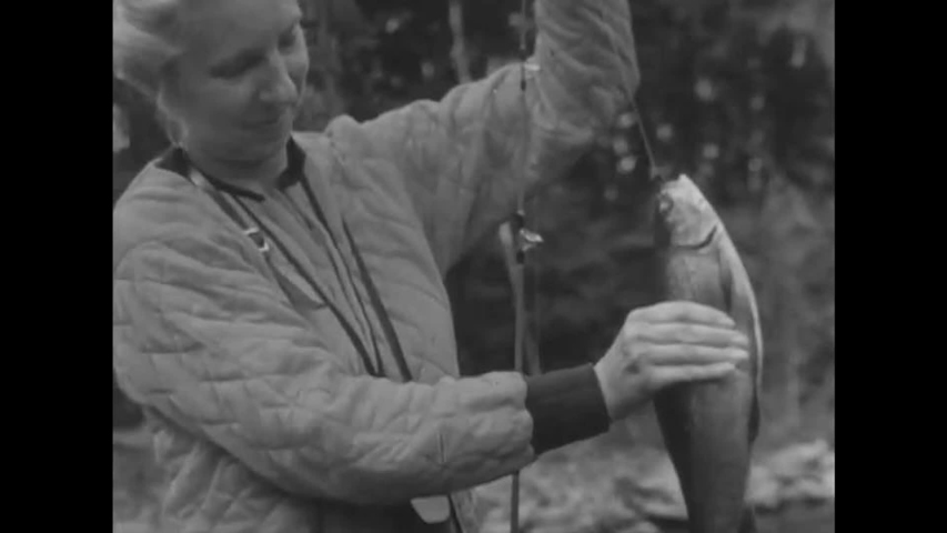 CIRCA 1950s - Shots of a peaceful lake, and a group of fishers eat dinner in Canada in the 1950s.