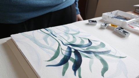 Artist painting with watercolor paint on paper