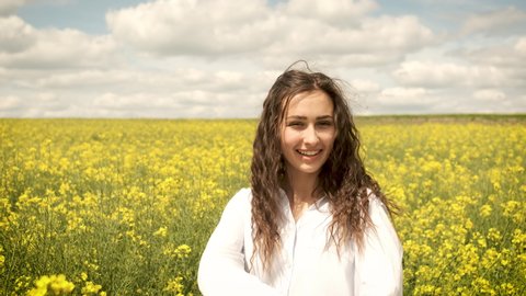 Happy girl on a spring yellow rapeseed spinning in front of the camera