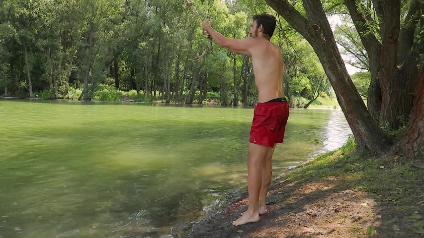 Guy jumping from rope swing hitting the water head down