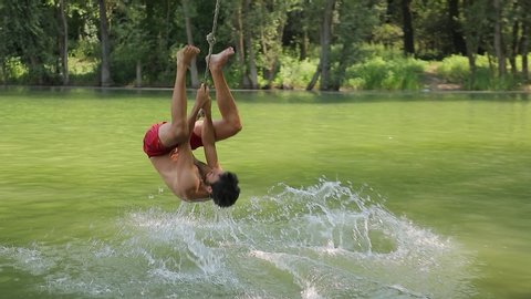 Guy jumping from rope swing hitting the water head down