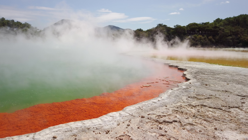 4K hand held stationary motion of close view and steam of the bubbling hot water in the thermal lake called the Champagne Pool at Wai-O-Tapu Thermal Wonderland at Rotorua,North Island,New Zealand Royalty-Free Stock Footage #1053985652
