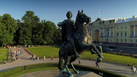 Petersburg / Russia - 07.02.2019 : Copper Horseman. Senate square historic attraction. Bronze sculpture St. Isaac's Cathedral. Many people tourists walk. Summer. Aerial motion close to hand of king