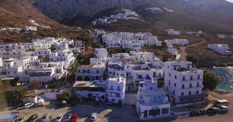 Greek island hill station with classic blue and white colored buildings and a car driving down a winding road in true C4k lossless Prores. Files are uncompressed for best cinematic quality.