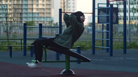 Стоковое видео: Girl doing exercise on bars outdoor. Sporty girl doing sit-ups on bars outdoors.