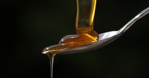 Honey Pouring On Spoon against black background